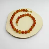 Collar de cuentas de piedra cornalina color naranja, con cierre de mosquetón dorado.