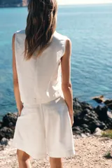 Bermuda blanca de tiro alto con cinturón con hebilla forrada, pinzas delanteras, bolsillos frontales y falsos bolsillos de vivo en espalda. Cierre frontal con cremallera, botón interior y ganchos.