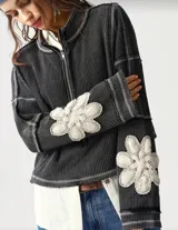 Sweater gris oscuro de punto waffle con cierre frontal, cuello alto y detalles de flores de encaje color crema en las mangas.