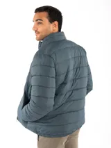 Campera puffer reversible color verde azulado con interior gris. Tiene cuello alto, cierre frontal y bolsillos laterales con cierre.