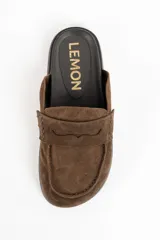 Zueco tipo mocasín destalonado confeccionado en gamuza color marrón, con suela de goma negra y plantilla anatómica.