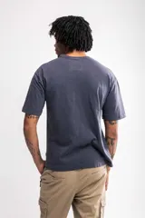 Remera gris con estampado frontal de la marca Atomic en rojo y blanco. Corte boxy fit.