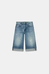 Bermuda de jean estilo jorts de tiro medio con efecto lavado. Presenta diseño de cinco bolsillos, detalle de roturas y bajo con dobladillo vuelto. Cierre frontal con cremallera y botón metálico.