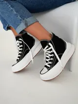 Championes tipo botita de caña alta con diseño bicolor, cuerpo en color negro y suela de plataforma gruesa en color blanco con base de goma.