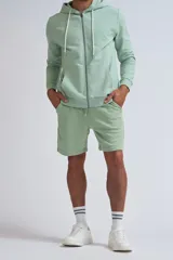 Chaqueta deportiva con cierre frontal completo, capucha con cordones ajustables y bolsillos tipo canguro, confeccionada en tejido de algodón en color verde menta.