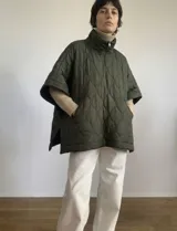 Poncho acolchado color vino tinto, con cuello alto y cierre frontal parcial. Presenta un patrón de costuras capitoné en forma de hoja o diamante y bolsillos delanteros.