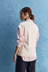 Chaleco de tejido de punto color beige claro, con cuello redondo y diseño de líneas limpias con hombros caídos y terminaciones acanaladas.