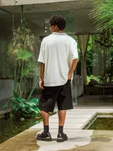 Bermuda negra de gabardina, corte ancho y largo, con bolsillos laterales.