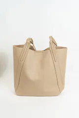 Bolso tipo tote de diseño minimalista, confeccionado en material texturizado color beige, con doble asa larga para llevar al hombro y costuras reforzadas en los laterales.