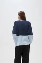 Sweater de tejido de punto con diseño color block, combinando azul marino en la parte superior y celeste en la inferior. Presenta cuello redondo a la base y mangas largas.