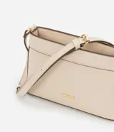 Cartera bandolera pequeña de material sintético color beige con detalles en marrón oscuro. Cuenta con cierre superior por cremallera, asa larga ajustable y placa metálica dorada con el logo de la marca en el frente.