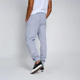 Pantalón de jogging negro con puños ajustados en los tobillos y cordón en la cintura. Presenta un escudo bordado en amarillo y negro en la pierna izquierda.