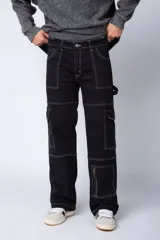 Pantalón tipo carpintero de corte relaxed fit y tiro medio, confeccionado en denim negro con costuras a contracolor en blanco. Presenta múltiples bolsillos cargo laterales, un bolsillo con cierre en la parte inferior y presillas utilitarias.