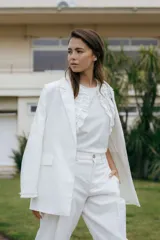 Blazer de lino blanco con solapas y detalles de volados en los puños, de corte recto y clásico.