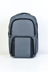 Mochila gris con detalles en negro, con dos compartimentos principales con cierre, un bolsillo frontal con cierre y bolsillos laterales.