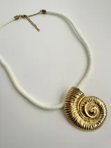 Collar con dije dorado en forma de concha de nautilus y cordón blanco.