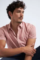 Camisa de manga corta con diseño a rayas verticales en color azul marino y blanco. Presenta cuello clásico, cartera abotonada frontal y logo bordado en el pecho. Posee un corte slim fit.