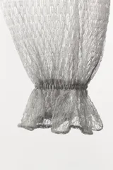 Pantalón abombacho semitransparente de tejido de encaje suave color gris, con tiro medio, cintura elástica y diseño con calados y volantes en los tobillos.