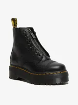 Bota Dr. Martens modelo Sinclair, color negro, de cuero Milled Nappa con textura granulada. Presenta una cremallera frontal extraíble, cordones, y se asienta sobre una suela de plataforma gruesa con costuras amarillas distintivas y una trabilla amarilla en el talón.