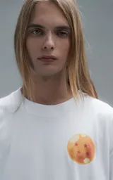 Remera blanca de corte oversize con cuello redondo y manga corta. Presenta una estampa central a todo color con personajes de Dragon Ball montados sobre el dragón Shenlong.