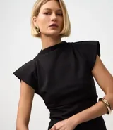 Blusa negra de crepé con cuello alto, mangas cortas con hombreras y bajo asimétrico con bico lateral.