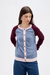 Cardigan de punto con diseño color block, presenta cuerpo en color celeste, mangas en color bordó y detalles de botones y bordes en color rosado. Posee cuello redondo y mangas largas.