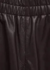 Pantalón de cuero ovino color bordó, de corte holgado estilo balloon, con cintura alta y puños ajustados en los tobillos.