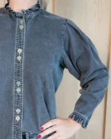 Camisa de manga larga con estampado de rayas verticales en tonos crudo y beige. Presenta cuello alto con volados, cierre frontal con botones dobles y puños con volados.