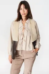 Chaleco de cuero marrón con interior y solapas de piel sintética color crudo. Diseño sin cierre, con corte recto y acabado texturizado.