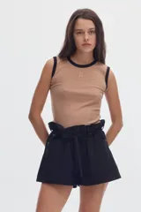 Musculosa de calce al cuerpo, en tejido rib color tostado, con cuello redondo y ribetes en contraste negros. Cuenta con un pequeño isotipo bordado en el centro del pecho.