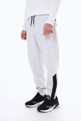 Pantalon de jogging de felpa en color gris melange, con cintura elástica ajustable mediante cordones, puños en los tobillos y paneles laterales en contraste de color negro en la parte inferior de las piernas.
