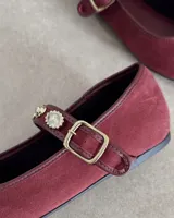 Ballerinas de gamuza color borgoña con correa sobre el empeine adornada con apliques de strass y hebilla metálica.