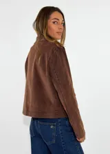 Chaqueta de pana color marrón, con solapas desflecadas, cierre frontal con botones y bolsillos delanteros con solapa desflecada.