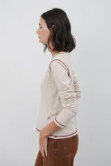 Remera de manga larga color marrón, con costuras a la vista en color blanco que resaltan los cortes de la prenda. Presenta un pequeño bordado blanco en la parte inferior y un corte recto.