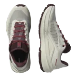 Championes de trail running Salomon Genesis 2, en color beige claro con detalles en bordó y rojo. Cuentan con capellada de Matryx®, sistema de ajuste rápido de cordones Quicklace, suela Contagrip® y tecnología Active Chassis para mayor estabilidad.