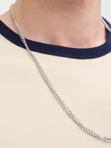 Remera de manga corta color beige, de corte relajado, con cuello redondo y ribetes en contraste de color azul marino en el cuello y los puños. Presenta un pequeño bordado en el pecho.