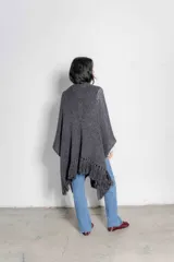 Ruana de tejido de punto grueso color gris con flecos en el ruedo.