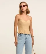 Blusa estilo corset color beige claro, con escote corazón y breteles finos. Presenta un corte ajustado en el torso y un volado peplum en el bajo.