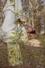 Conjunto de dos piezas confeccionado en lana merino, compuesto por un buzo de corte holgado con mangas acampanadas y un pantalón de pierna ancha con cintura elastizada y bolsillos laterales. Ambas prendas presentan un diseño artesanal con técnica de ecoprint en tonos tierra y azulados sobre base color crema.