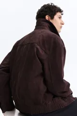 Campera marrón de tejido suave con acabado cepillado, cuello camisero, cierre frontal y bolsillos laterales.