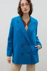 Blazer de lana con diseño bicolor, cuerpo en color negro y mangas en color crema. Presenta un corte holgado, cierre cruzado con doble botonadura y solapas amplias en contraste.