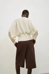 Jersey de cuello redondo color blanco, con manga larga tipo murciélago y acabados en rib elástico.