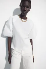 Camiseta blanca de corte slim fit con cuello redondo y mangas cortas abullonadas en tejido a tono.
