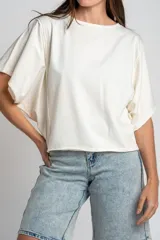 Remera oversize de algodón blanco crudo, con cuello redondo y mangas cortas anchas de corte relajado.
