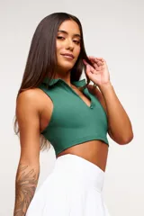 Top deportivo negro, estilo crop top, con cuello polo y escote en V. Presenta tirantes anchos y corte ajustado al cuerpo.