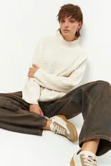 Polera color crema de tejido tramado, cuello alto y mangas largas holgadas.