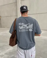 Remera oversize de color verde militar con efecto acid wash y diseño estampado en la espalda que incluye un camión de remolque y texto alusivo.