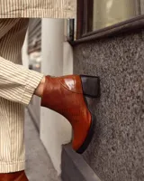 Botinetas de cuero vacuno con textura tipo reptil en color marrón chocolate. Presentan un diseño de caña media con cierre posterior, puntera redondeada y suela de goma con taco cuadrado robusto.