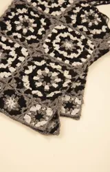 Remera sin mangas de algodón orgánico con diseño de granny squares tejidos a crochet en tonos negro, blanco y gris, con escote cuadrado y tirantes anchos.