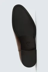 Bota estilo chelsea de cuero color marrón, con paneles elásticos laterales, tirador trasero y horma en punta con suela de tacón bajo.